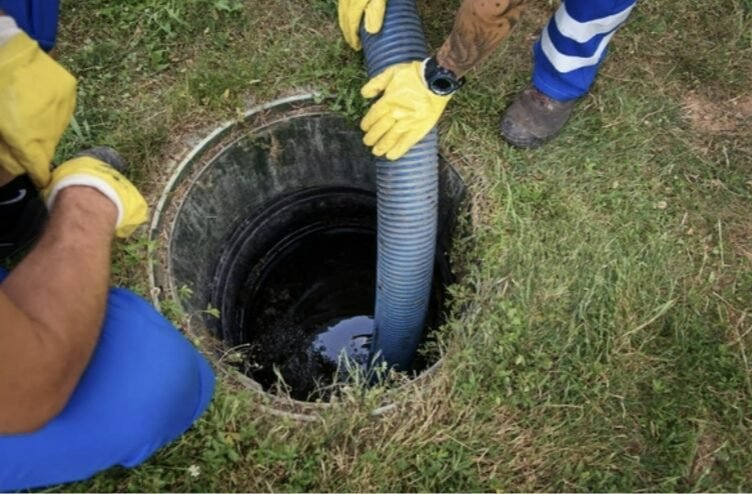 Agents d’assainissement nettoyant une bouche d’égout en extérieur avec une pompe bleue