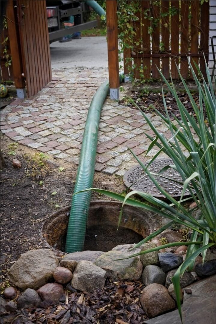 Pompage fosse septique Val-d’Oise (95) – tuyau d’aspiration en intervention dans un jardin